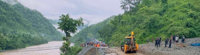 त्रिशूली नदी के पास जेसीबी के पास खड़े लोग।